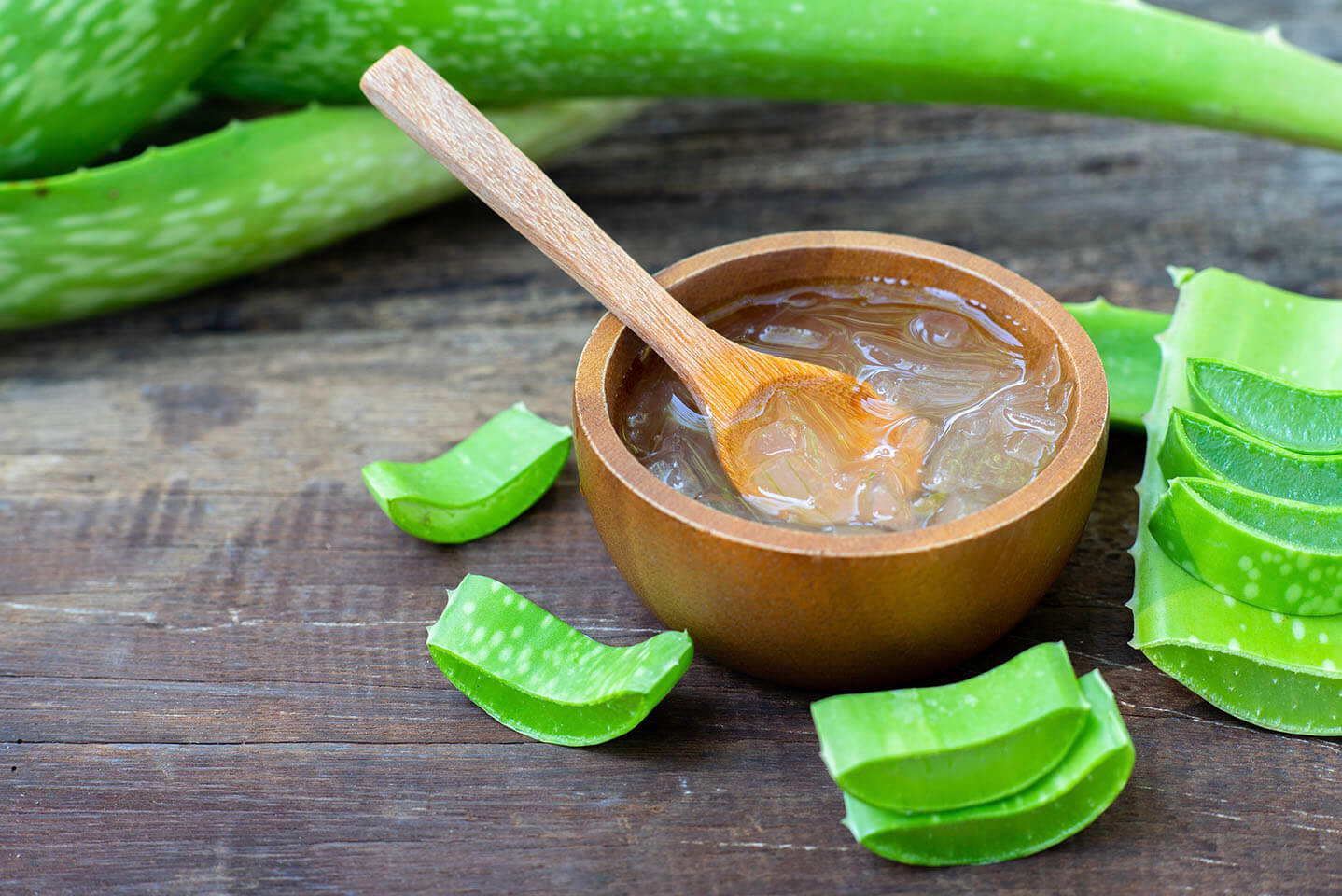Fresh aloe vera plant, stem slices and gel on wooden background,