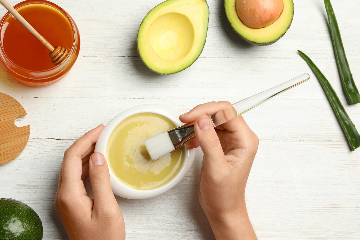 Woman with handmade face mask, brush and ingredients at white wo