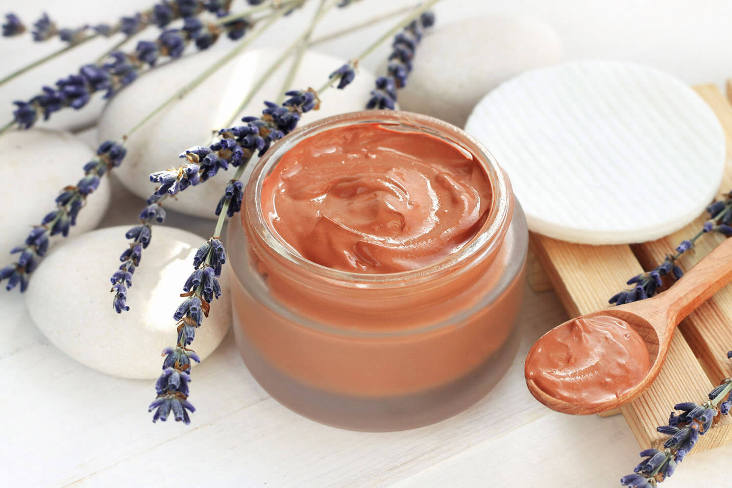 Cosmetic red clay mask mixed in jar, dried lavender flower twigs